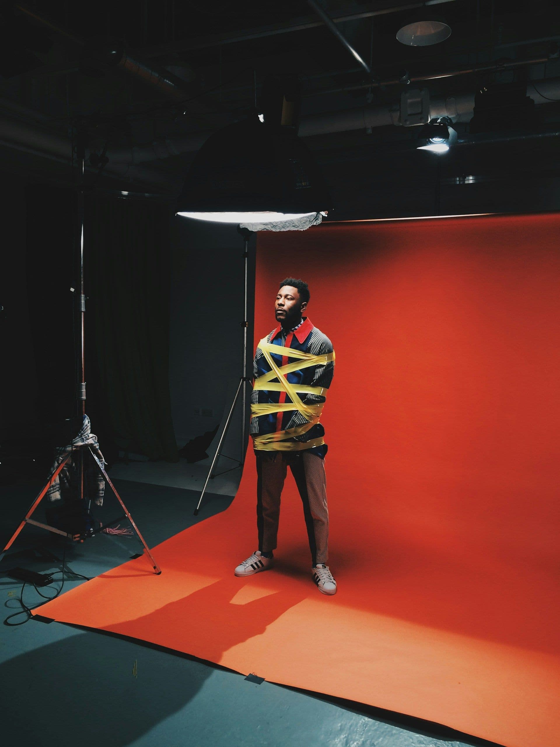 Man standing behind an orange backdrop in a studo taking a photograph